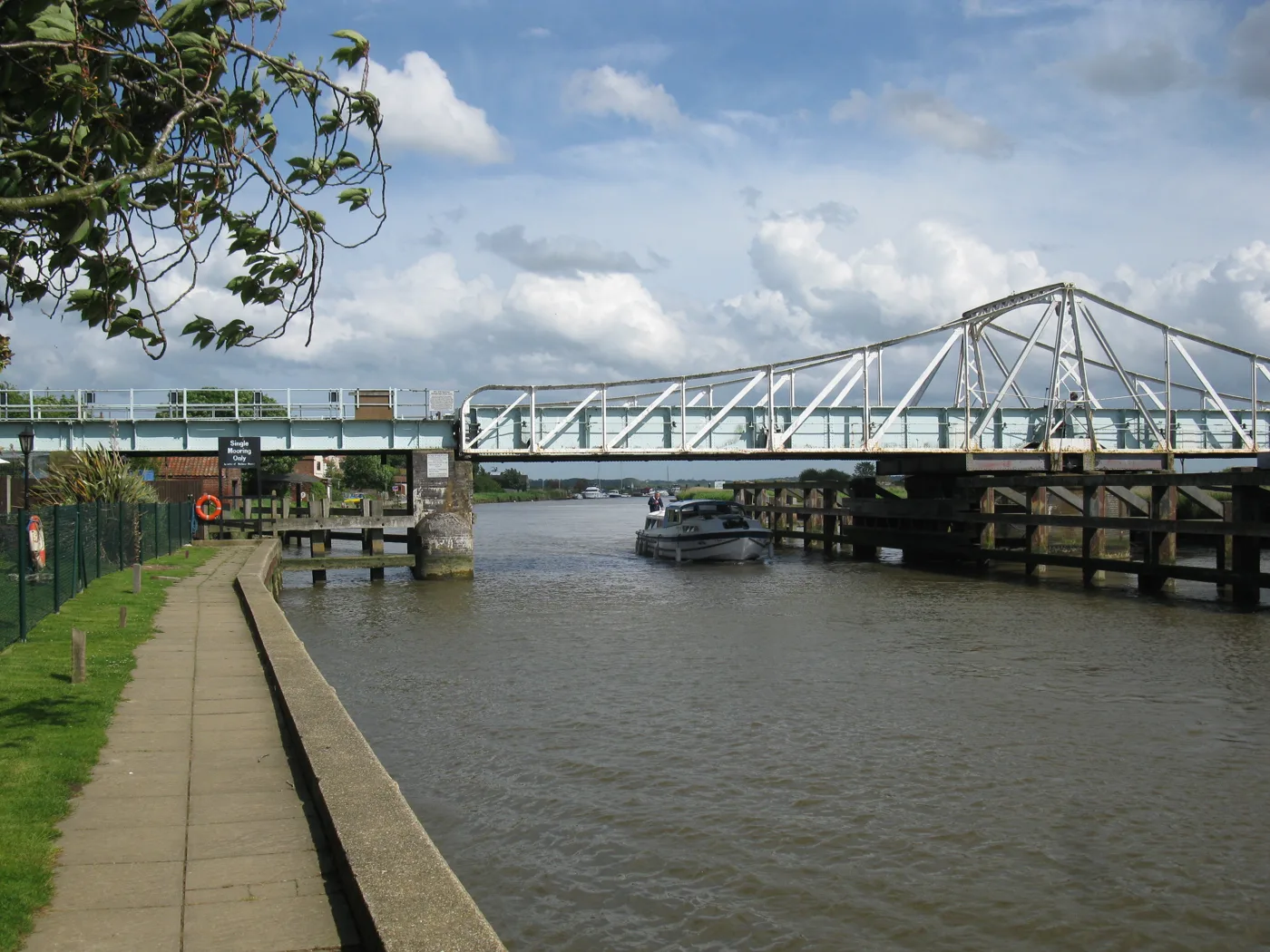Reedham swing bridge over the River Yare, with a cruiser passing beneath the fixed span. Most Broads boats clear the bridge without it opening.